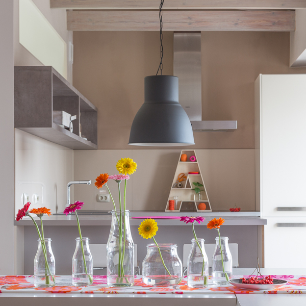 Urban kitchens have a tendency to be small. By keeping the color in the kitchen nook more neutral, the space feels more comfortable. The addition of fresh flower arrangements makes for a welcoming dining atmosphere.